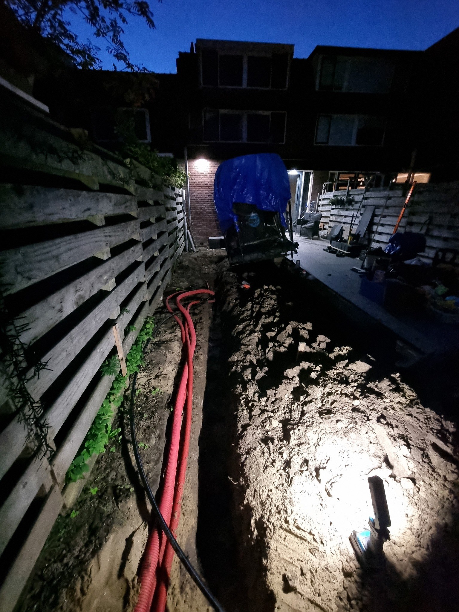 Gegraven sleuf met leidingen tijdens de werkzaamheden in de avond