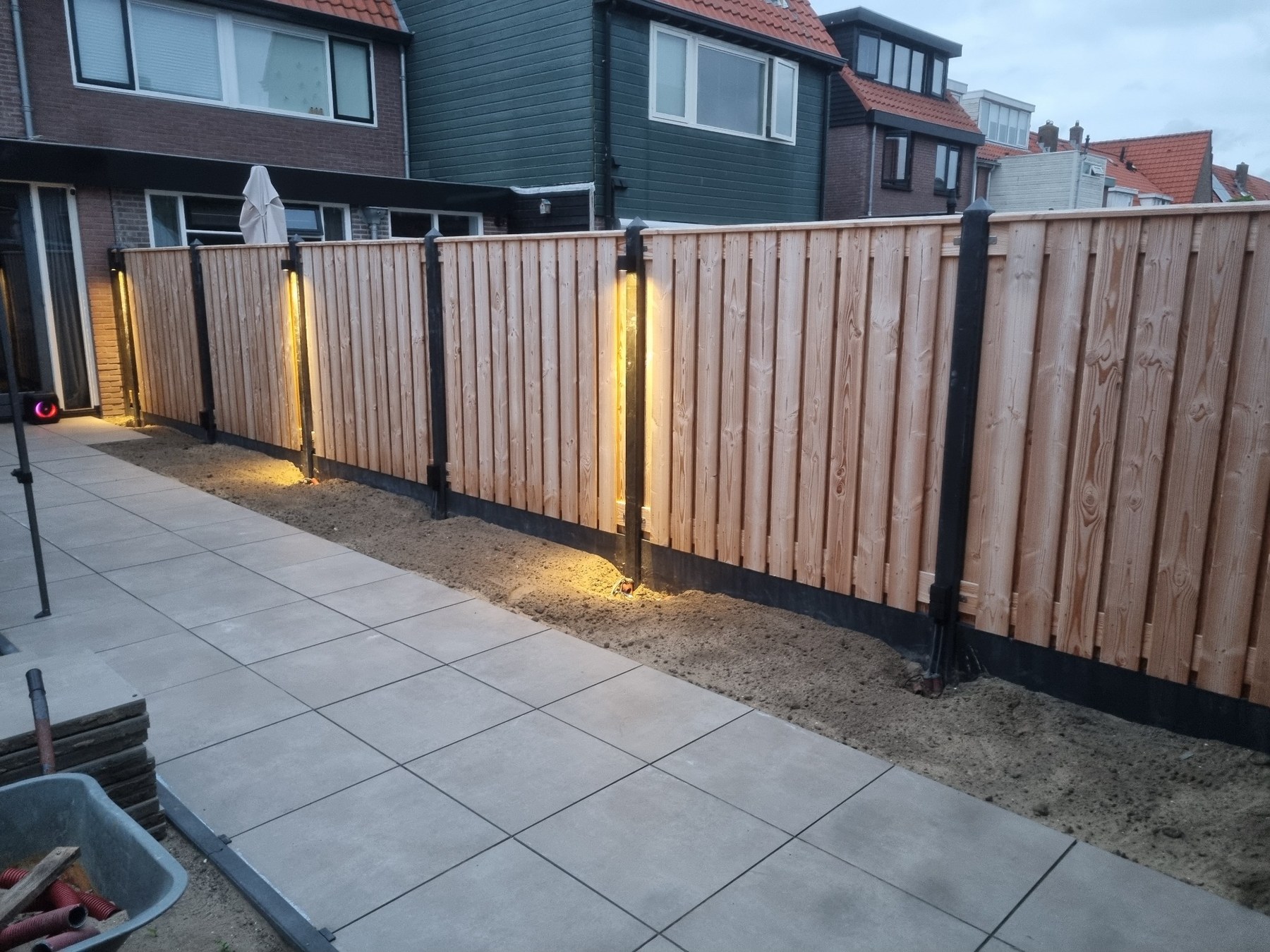 Aangelegde tuinverlichting langs houten schutting