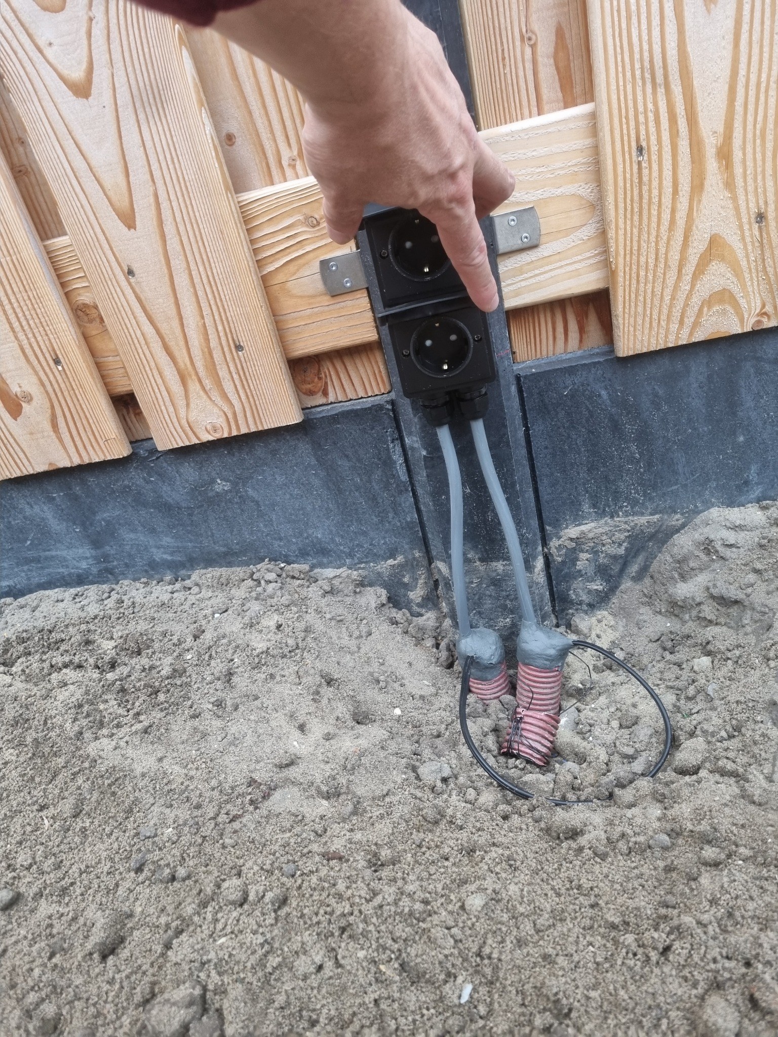Dubbele buitenstopcontacten gemonteerd op een schuttingpaal